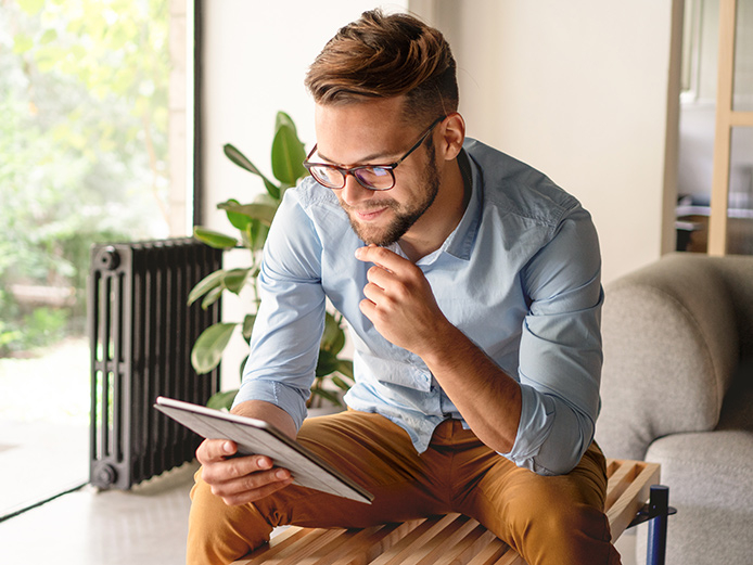 Man sitting, leaning forward to look at a tablet