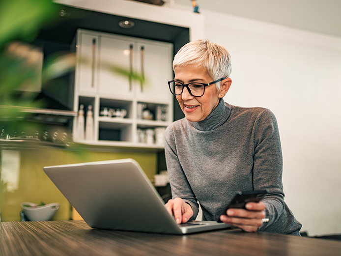 Older woman sitting at table working on laptop