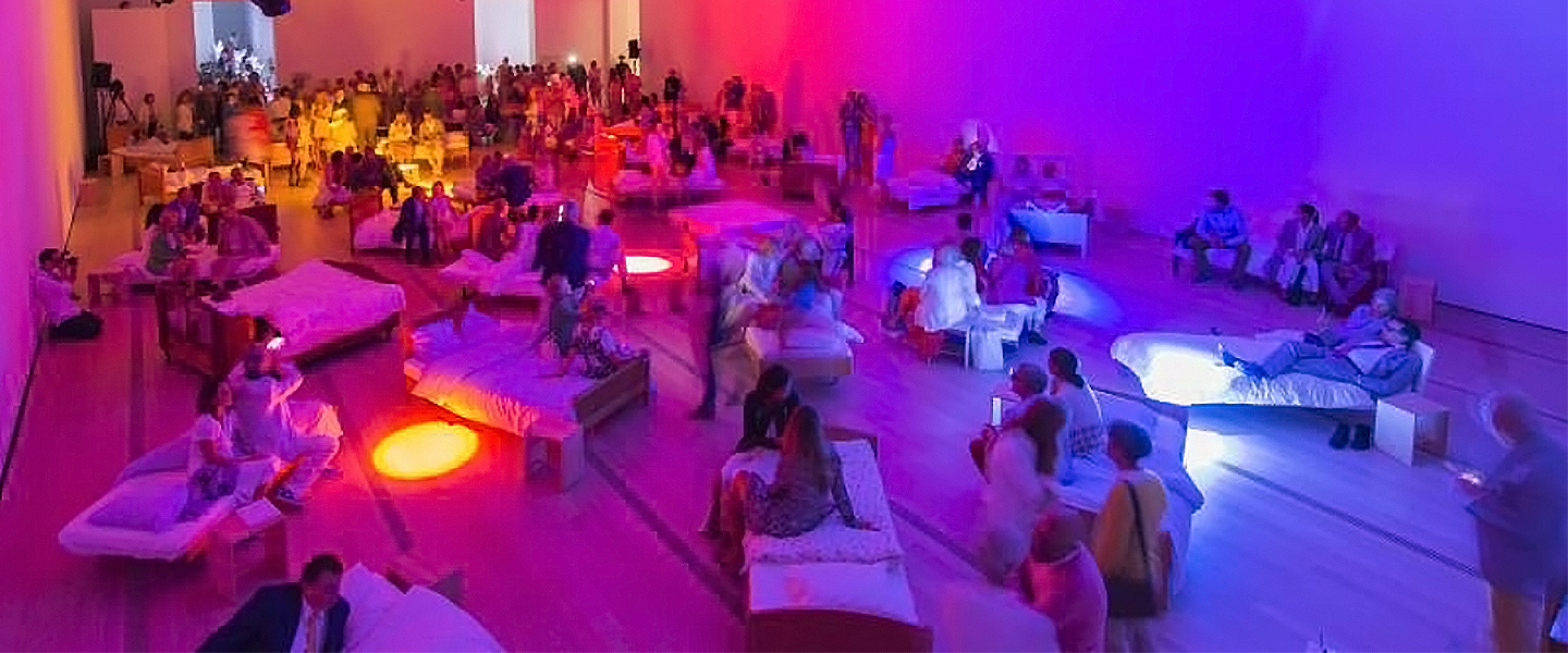 Room tinted in red and blue lighting, with people relaxing on white seats