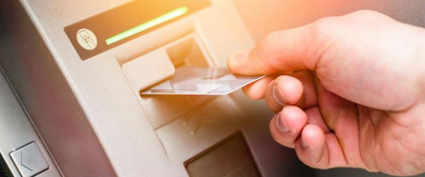 Hand sliding credit card into an ATM
