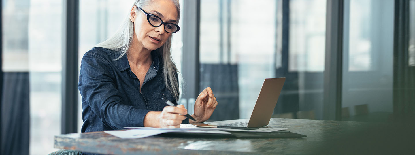 Grey-haired professional-looking woman concentrating while working at her laptop
