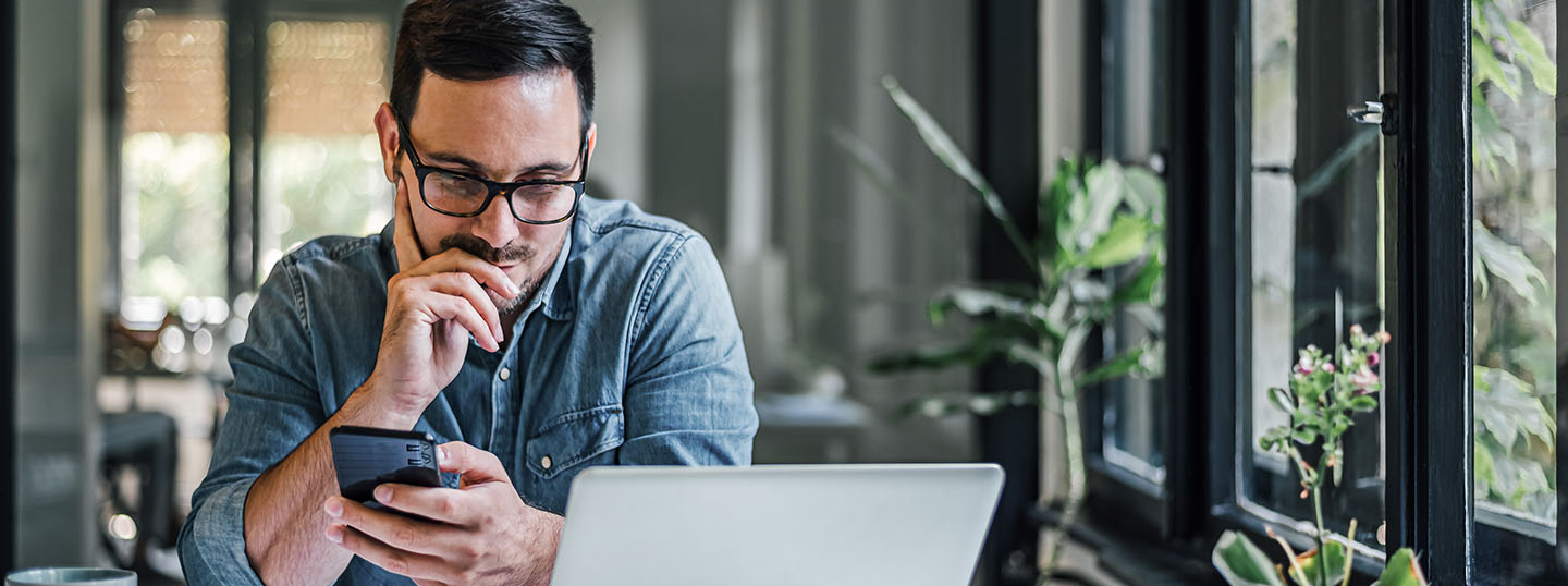 A man looks thoughtfully at his laptop 