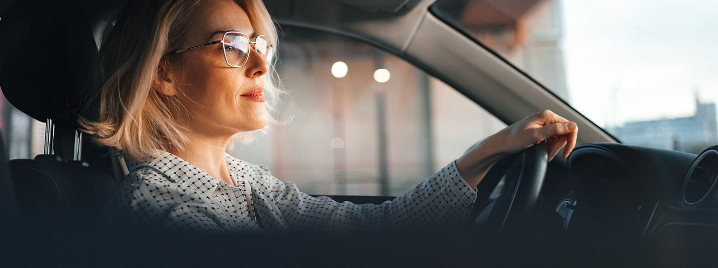 Image of a blonde white woman happily driving and concentrating on the road ahead