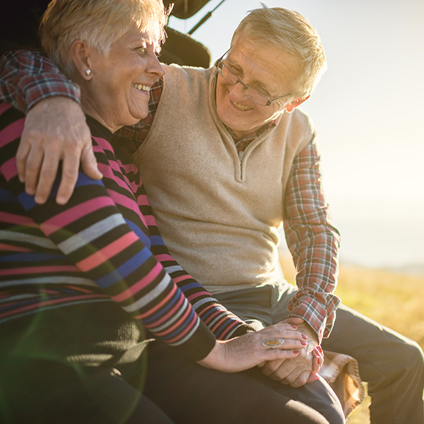 Older couple hugging in their boot in the sunshine and smiling at each other