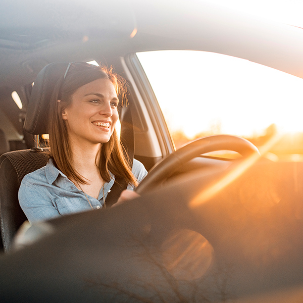 Woman driving her car in the sunset