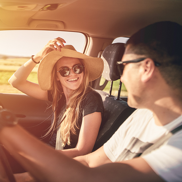 Young couple laughing at each other whilst driving in the sun