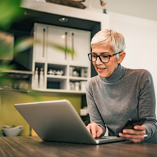 Older woman sitting at table working on laptop