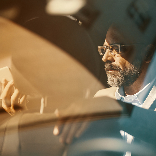 Man photographed through the reflections of a windscreen of a car