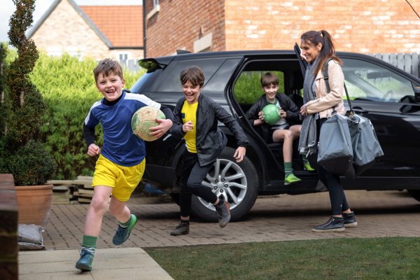 Children running out of a car with footballs