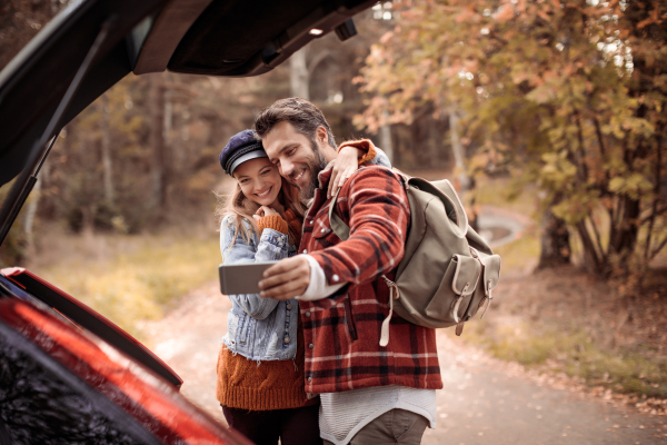 Couple taking selfie outside their car with trees in the background